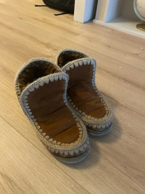 MOU, perfekta höst/vinter skor - Snygga bruna skor i mocka med högt skaft och tjockt ullfoder. Dekorativa stickade detaljer i beige längs kanterna. Perfekta för att hålla fötterna varma ute under kalla och snöiga dagar. Sula i gummi för extra grep