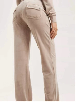  Juicy couture sett  - Mjuk och skön loungewear-set i beige velour med huva, dragkedja och fickor fram. Byxorna har raka ben och fickor med lock bak. Perfekt för chill dagar hemma. Snygg och avslappnad passform.