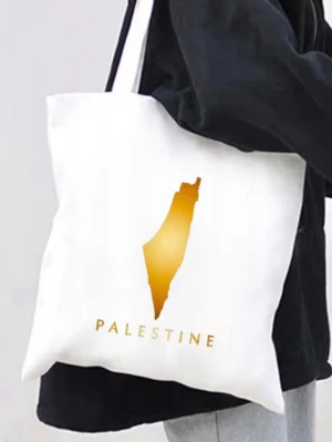 Vit shoppingväska med guldtryck - Snygg vit tygkasse med ett stilrent guldtryck av Palestinas karta och texten 'PALESTINE' i matchande guld. Perfekt att bära till skolan eller stan, rymmer mycket och har långa axelband. Väskan är i klassisk rektangulär form och tillverkad i tyg.