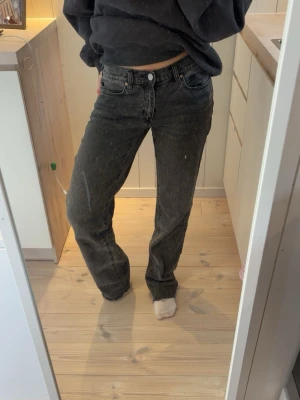 Svarta raka jeans med hög midja - Säljer ett par svarta raka jeans med hög midja och klassisk femficksmodell. Jeansen har en snygg tvättad look och stängs med knapp och dragkedja. Perfekta till en avslappnad stil och passar till det mesta i garderoben.