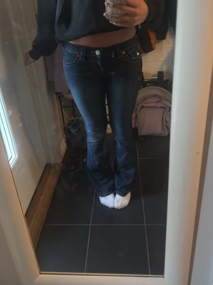 Mörkblå bootcut jeans från true religion - Säljer ett par mörkblå bootcut jeans från true religion med snygga slitningar och kontrastsömmar. Jeansen har låg midja, klassiska fem fickor och detaljer i kopparfärg. 