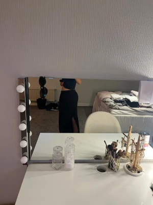 Svart långkjol med slits - Stilren svart långkjol med hög midja och en snygg slits på sidan. Kjolen har en rak passform och är perfekt för dig som gillar en enkel men trendig look. Passar till många olika outfits och är lätt att matcha med både toppar och tröjor. Slitsen där bak har spruckit lite i sömmen men det går att enkelt sy ihop!
