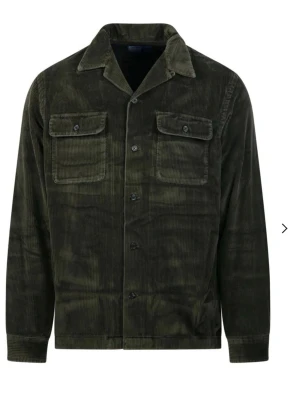 Mörkgrön overshirt i manchester Ralph lauren - Stilren mörkgrön overshirt i manchestertyg med klassisk krage och knäppning framtill. Två bröstfickor med lock och knappar ger en cool utility-vibe. Perfekt lager på lager-plagg för dig som gillar en avslappnad men trendig look. Skriv till mig om ni vill ha bilder på hur den sitter Med vänlig hälsning, Oliwer!
