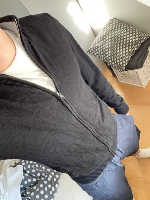 Svart ziptröja från Marone - Svart fullzip från Pier one med hög krage och hel dragkedja. Tröjan har två fickor framtill och ribbade muddar vid ärmslut och nederkant. Perfekt för en avslappnad och stilren look. Storlek S