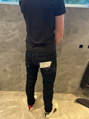 Mörkblå Replay Hyperflex jeans - Snygga mörkblå slim fit jeans från Replay Hyperflex med klassiska fem fickor och vita kontrastsömmar. Jeansen har stretchigt material som ger en skön passform och stilren look. Perfekta för dig som gillar en modern och smal siluett.