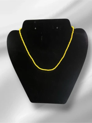 Gult halsband med små pärlor - Snyggt halsband med små, runda pärlor i klar gul färg. Halsbandet har en enkel och stilren design med guldfärgat spänne. Perfekt för att addera en färgklick till din outfit. Materialet är plastpärlor.
