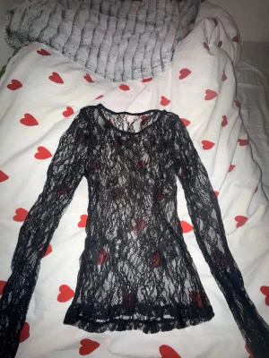 Svart spetsblus från Nelly - Säljer en svart långärmad spetsblus från Nelly. Toppen är helt genombruten i spets och har en figurnära passform. Perfekt att styla med ett linne eller bralette under för en edgy look.🖤🖤säljer då den är för tajt för mig (ingen stretch)