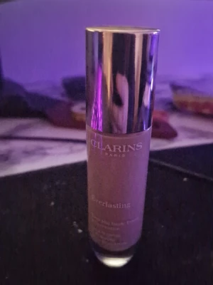 Clarins Everlasting Foundation - Clarins Everlasting Foundation i glasflaska med silvrig pumpkork. Flytande foundation i beige ton som ger en matt finish och lång hållbarhet. Flaskan har elegant design och text i vitt. Perfekt för dig som vill ha en återfuktande och täckande bas. Färgen heter 111N 