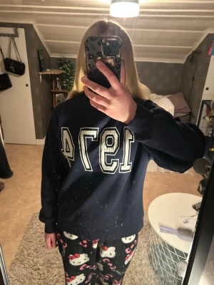 Mörkblå sweatshirt med tryck 1974 - Säljer en mörkblå sweatshirt med stort vitt tryck '1974' på framsidan. Tröjan har en klassisk rund halsringning och långa ärmar. Materialet känns mjukt och bekvämt, perfekt för en avslappnad stil. 