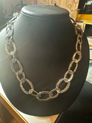 Kedjehalsband i silverfärgad metall - Säljer ett chunky halsband med stora, ovala länkar i silverfärgad metall. Länkarna har en hamrad, texturerad yta som ger ett coolt och trendigt intryck. Perfekt för dig som vill ha ett statement piece till din outfit.