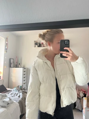 Vit pufferjacka med hög krage - Säljer en vit pufferjacka med hög krage och dragkedja framtill. Inte den allra tjockaste men fungerar både under vinter, höst och vår!