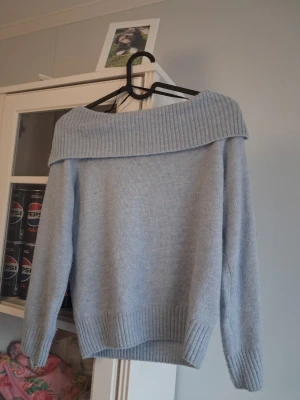 Ljusblå off shoulder stickad tröja - Säljer en ljusblå stickad tröja från H&M med bred off shoulder-krage och ribbade muddar. Tröjan har en avslappnad passform och är perfekt för dig som gillar en stilren och mysig look. Materialet känns mjukt och behagligt mot huden. Använt fåtal gånger!💞