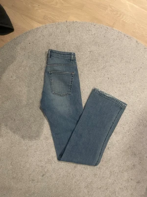 Blå bootcut jeans med hög midja -  Jeansen har en lätt tvättad look och raka ben som går ut lite nedtill. Perfekta till sneakers eller boots och passar till många olika stilar.