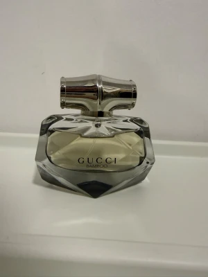 Gucci Bamboo Eau de Parfum - Gucci Bamboo Eau de Parfum i en elegant, multifacetterad glasflaska med silverfärgat lock. Doften är sopistikerad och flaskan har en exklusiv design som verkligen sticker ut på parfymhyllan. Perfekt för dig som gillar nischade och lyxiga dofter.