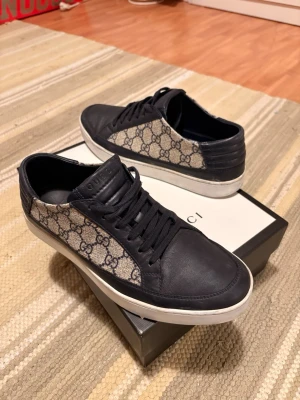Gucci skor - Snygga sneakers från Gucci med klassiskt GG-monogram i beige och mörkblått. Skorna har ovandel i canvas och läderdetaljer, samt vit sula. Perfekta för dig som vill ha en lyxig och trendig look med streetkänsla. Låda och dustbags! 🔥🙏