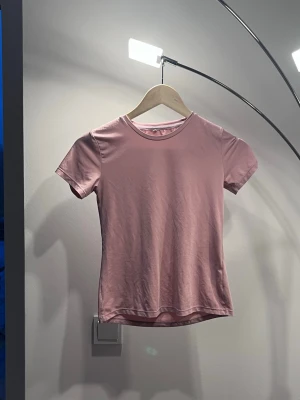 Ljusrosa basic t-shirt - En enkel och stilren ljusrosa t-shirt med rund hals och korta ärmar. Perfekt att matcha med jeans eller kjol för en clean look. Tillverkad i mjuk bomull som känns skön mot huden.