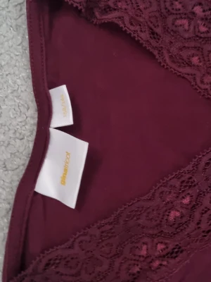 Vinröd långärmad topp från Gina Tricot - Vinröd långärmad topp från Gina Tricot med v-ringning och spetsdetaljer vid halsen. Tunn och mjuk i materialet, perfekt för lager på lager eller som den är. Enkel men ändå elegant design som passar till mycket.