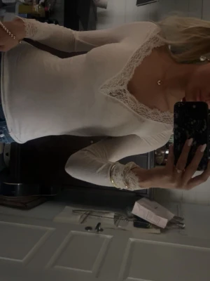 Vit top från Intimissimi  - Säljer en superfin vit långärmad topp från Intimissimi med v-ringning och spetsdetaljer vid halsringning och ärmslut. Sitter tajt och är i cashmere blandning. Inga defekter futon en pytte liten fläck som knappt syns. 