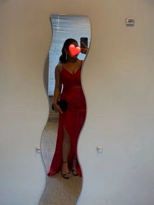 Röd långklänning med slits - Röd långklänning med smala axelband och v-ringning. Perfekt för balen eller andra festliga tillfällen.  