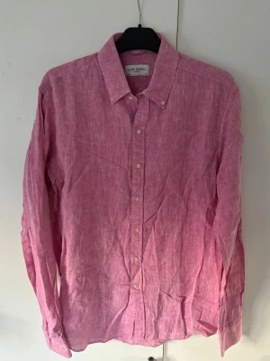 John Henric skjorta M rosa - Denna extremt snygg populära John Henric linneskjorta i storlek M säljes. Väldigt fint skick utan några defekter som helst. Rosa färg perfekt nu till sommaren och tveka inte vid minsta fråga eller fundering! 