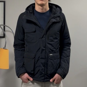 Woolrich Fieldjacket - Säljer denna asfeta Mörkblå/svarta Woolrich fieldjackan! Jackan är i väldigt bra skick, enbart lite lagad hos en skryddare men inget som syns! Självklart äkta! Size 14 vilket motsvarar typ M, modellen på bilden är 182cm lång ish. Skriv vid funderingar!