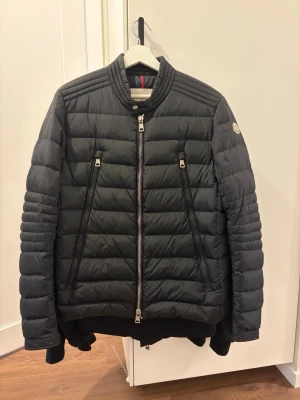 Moncler jacka  - Säljer min Moncler dunjacka i svart. Väldigt snygg och stilren modell som passar till det mesta. Jackan är varm men samtidigt lätt och bekväm att bära.  Jackan är i fint skick och alla dragkedjor och detaljer fungerar som de ska. QR-tag för äkthet sitter kvar på insidan.  Kvitto finns tyvärr inte kvar.  Perfekt jacka till höst och vinter.  Kan skickas eller mötas upp. 