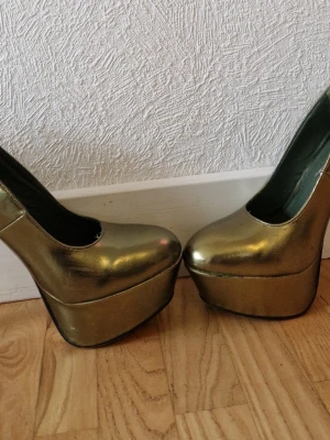 Grönmetallic platåpumps med hög klack - Coola grönmetallic pumps med rejäl platåsula och hög klack. Skorna har rundad tå och är tillverkade i ett syntetmaterial med metallicfinish. Perfekta för dig som vill sticka ut och älskar statementskor.
