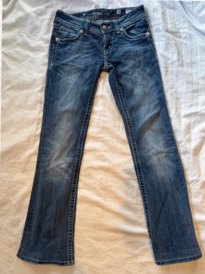 Miss Me bootcut jeans med brodyr - As snygga unika bootcut jeans från Miss Me med slitningar och broderade detaljer på bakfickorna.    Jeansen har låg midja,unika nitar. Säljer endast för dom är för små så har endast provat dom ej använt, måtten finns på bilderna men skulle säga att de är storlek xs-s. Skriv om ni har frågor! Pris kan diskuteras!!!!