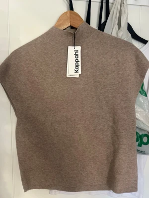Beige stickad väst från Kappahl - Snygg beige stickad väst från Kappahl med hög hals och slätstickad design. Perfekt att styla över en skjorta eller långärmad tröja för en trendig lager-på-lager-look. Mjuk och skön kvalitet som passar till många outfits. HELT NY OCH ALDRIG ANVÄND!! Skit snygg!!❣️