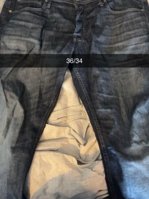 Mörkblå jeans från Jack & Jones - Snygga mörkblå jeans från Jack & Jones i modellen Tapered Mike. Jeansen har klassisk femficksdesign, guldfärgade detaljer och är tillverkade i denim. Perfekta för en avslappnad och trendig stil.