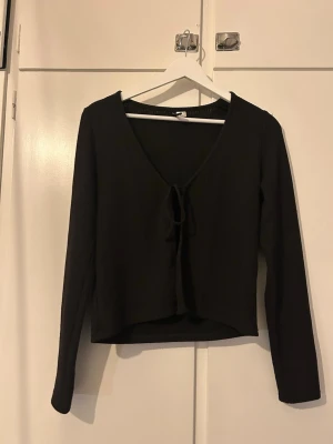 Kofta med knytband - Svart kofta från HM Divided i storlek M. Två knytband fram som skapar en fin och gullig look. Den har två små revor bak, men jag upptäckte de först när jag tittade väldigt nära och noga.