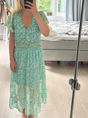 Flerfärgad blommönstrad klänning från Stradivarius storlek S - Otroligt fin mönstrad och flerfärgad klänning från Stradivarius i storlek S. köptes för 479kr men den har aldrig kommit till användning. superskönt material. nyanser av grönt, blått, turkost