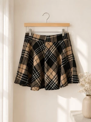 Rutig kortkjol  - Supersnygg rutig kortkjol i svart, beige och grå toner. Kjolen har en klassisk A-linjeform och är tillverkad i en mjuk ullblandning som ger en trendig och mysig känsla. Perfekt att styla med stickad tröja eller boots för en cool look.