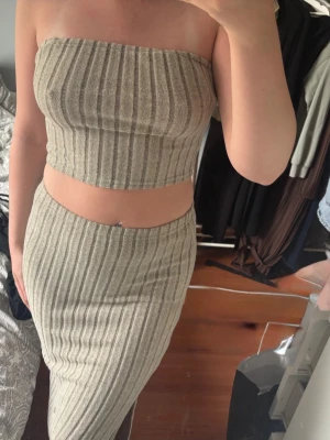 Beige ribbad långkjol med slits - Sättet kommer tillsammans, Trendig beige långkjol med ribbad struktur och vertikala ränder. Kjolen har en smal passform och en liten slits på sidan för extra stilpoäng. Perfekt att matcha med crop tops för en snygg och avslappnad look.