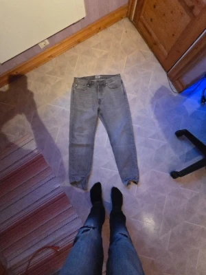 Gråa regular fit, 157 jeans, seattle - Säljer ett par gråa jeans i rak modell med fem fickor och normal midja. Jeansen har klassisk design med dragkedja och knapp framtill samt två bakfickor. Perfekta för en avslappnad och stilren look.