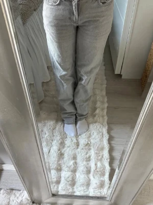 Grå raka jeans med låg midja - Säljer ett par snygga grå jeans med rak passform och låg midja. Jeansen har klassiska fem fickor och stängs med dragkedja och knapp. Perfekta till en avslappnad stil och lätta att matcha med olika toppar.