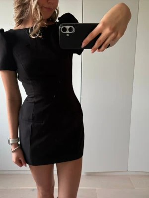 Svart kort klänning med puffärm - VIRAL ZARA KLÄNNING Snygg svart kort klänning med puffärmar och figurnära passform. Klänningen har rund halsringning och är tillverkad i ett slätt material som ger en stilren look. Perfekt för dig som gillar minimalistisk och trendig stil.