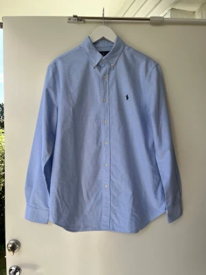 Ljusblå skjorta från Ralph Lauren - Klassisk ljusblå skjorta från Ralph Lauren med button-down krage och broderad logga på bröstet. Mycket bra skick. Priset är inte hugget i sten. Hör av dig om du har några frågor!
