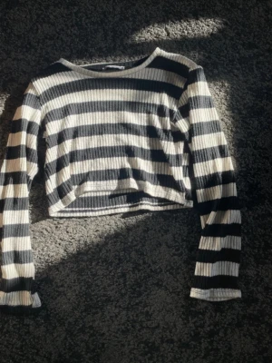 Långarmad randig Crop top - Svart/vit randig Crop top/magtröja med långa armar. Har köpt den second hand men inte använt något. Är i fint skick! Känns tjockare i materialet.