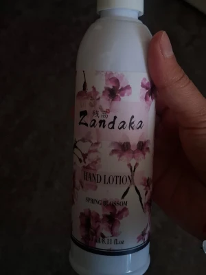 Zandaka Hand Lotion Spring Blossom - Handlotion från Zandaka med doft av Spring Blossom. Flaskan är vit med blommigt rosa motiv och svart text. Perfekt för att återfukta händerna och ge en fräsch känsla.