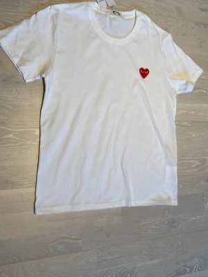 Vit t-shirt från Comme des Garçons Storlek L/M - Vit t-shirt från Comme des Garçons Play med det ikoniska röda hjärtat broderat på bröstet. Klassisk rund hals och korta ärmar. Tillverkad i mjuk bomull som känns skön mot huden. Priset kan diskuteras och skickar inom 24 Tim☺️💨