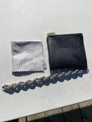 Silverfärgat tvinnat armband Kejsar - Snyggt armband i silverfärg från Kejsar med tvinnad design. Armbandet har en robust och stilren look, perfekt för att lyfta din outfit. Levereras med originalpåse och putsduk med Kejsar-logga. Materialet är metall med blank finish.