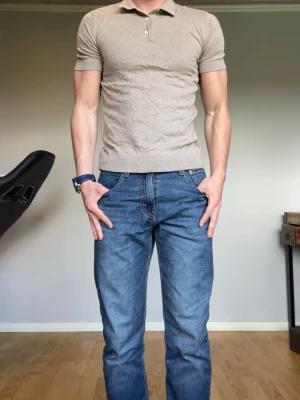 Beige kortärmad pikétröja - Säljer en stilren beige pikétröja med korta ärmar och klassisk krage med knappslå. Tröjan har en slim passform och är tillverkad i ett mjukt bomullsmaterial som känns skönt mot huden. Perfekt för dig som gillar en clean och enkel look.