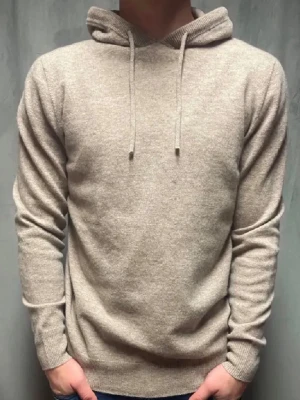 Merinoull hoodie - Säljer en stilren beige hoodie med huva och dragsko. Tillverkad i en mjuk och skön ullmix som känns lyxig mot huden. Hoodien har ribbade muddar vid ärmslut och nederkant för en snygg passform. Perfekt för dig som gillar en clean och enkel look.