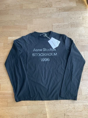 Acne studios longsleeve  - Svart långärmad topp från Acne Studios med tryck 'Acne Studios STOCKHOLM 1996' framtill. Tillverkad i mjuk bomull och har en klassisk rund halsringning. Perfekt för en clean och stilren look.