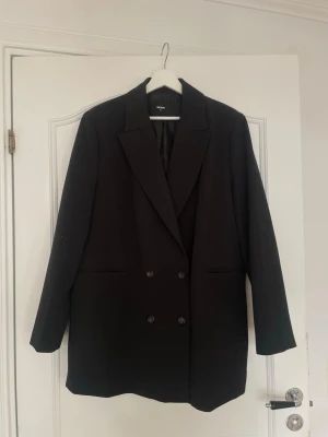Oversized kavaj - Stilren svart oversized kavaj från Bik Bok med dubbelknäppning. Kavajen har två fickor frmtill och en slits backtill. Perfekt för dig som gillar en trendig och avslappnad look.