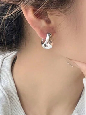  silverfärgade örhängen - Säljer ett par chunky örhängen i silverfärgad metall med en modern, böjd form. De har en blank, spegelblank yta och är perfekta för dig som gillar statement-smycken. Märke saknas på örhängena.