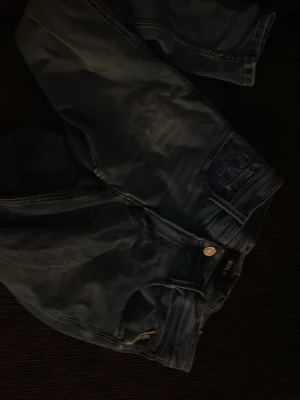 Replay jeans - Snygga blå jeans från Replay i rak modell. Klassisk femficksdesign med knappgylf och detaljerade sömmar. Jeansen har en mörk tvätt och är tillverkade i bomull för en bekväm känsla. Perfekta för en avslappnad och trendig stil.