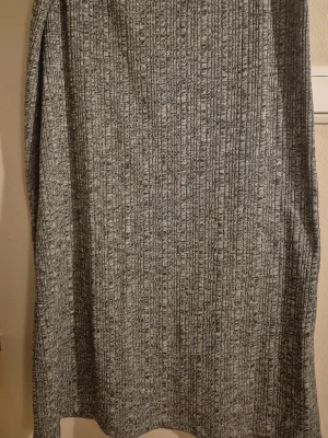 Grå ribbad midilångkjol från Lindex - Säljer en gråmelerad midi / långkjol från Lindex i ribbad stickad kvalitet (79 cm lång). Kjolen har en rak passform och är supermjuk och skön och elastiska.