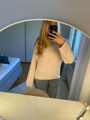 Ljusrosa kabelstickad tröja H&M - Mysig ljusrosa kabelstickad tröja från H&M med rund halsringning och långa ärmar. Tröjan har ett klassiskt flätmönster och ribbade muddar vid ärmslut och nederkant. Perfekt för lager på lager under kyliga dagar. Köptes för 300kr